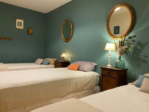 Cette chambre comprend 2 lits et un miroir mural. dans l'établissement Maison 1823 - Suites de charme à Garons, à Garons