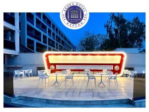 einer Bank mit Stühlen und einem Tisch vor einem Gebäude in der Unterkunft Hotel Agora in Neptun