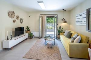 un soggiorno con un divano giallo e una TV di Mi Casa Su Casa a Città di Kos