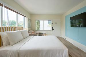ein Schlafzimmer mit einem großen weißen Bett und einem Sofa in der Unterkunft Aloha Fridays in Miami Beach