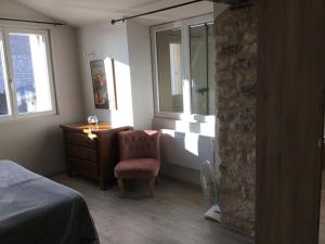 a bedroom with a chair and a dresser and windows at Maison de Louna in Noailles