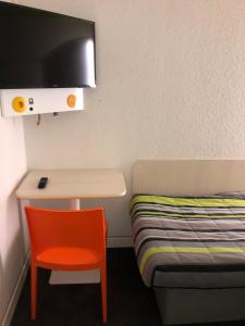 een kleine kamer met een bureau en een bed bij N&Z HOTELS in Trappes