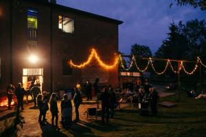 a group of people standing outside of a building at night at CAMP Agroturystyka Gorzelnia Gwieździn in Gwieździn