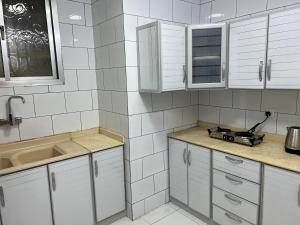a white kitchen with white cabinets and a sink at Hakimdom Hostel in Riyadh