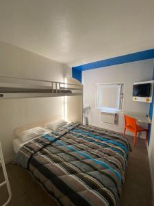 een slaapkamer met een bed en een bureau met een stoel bij N&Z HOTELS in Trappes