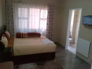um quarto com uma cama em frente a uma janela em Chisam Guest Lodge Pty Ltd em Joanesburgo