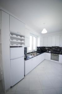 a white kitchen with white cabinets and a sink at Vila Kokoneshi in Divjakë