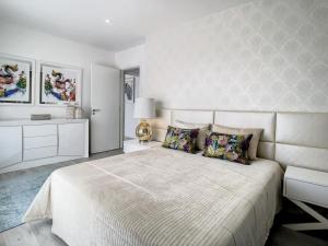 a bedroom with a large bed and a white wall at Rancho Tá-Mar Apartment Nazaré Beach in Nazaré