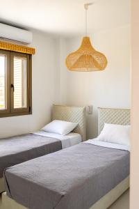 a bedroom with two beds and a chandelier at Saint Nicholas Resort - Villas in Kithnos