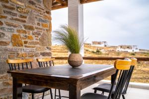 a table with chairs and a vase with a plant on it at Saint Nicholas Resort - Villas in Kithnos