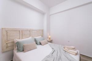 a white bedroom with a large white bed with pillows at Central apartments “Evanthia” in Pitsidia