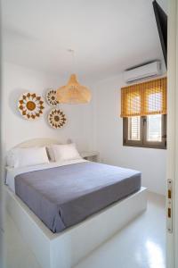 a white bedroom with a bed and a window at Saint Nicholas Resort - Villas in Kithnos