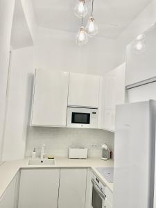 cocina blanca con armarios blancos y microondas en Picasso's Tres Puertas 4 bedrooms en Málaga