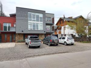 three cars parked in a parking lot in front of a house at Departamento Ramayon in San Martín de los Andes