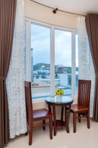 ein Esszimmer mit einem Tisch, 2 Stühlen und einem Fenster in der Unterkunft Queen Garden Hotel & Apartment in Vũng Tàu