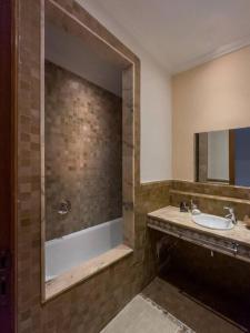 een badkamer met een wastafel, een douche en een spiegel bij Très joli Appart à la palmeraie coup de cœur in Marrakesh
