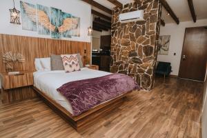 1 dormitorio con cama y pared de piedra en Oasis 444 en San Marcos