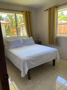 a bedroom with a white bed with a window at Miki Miki Surf Lodge in Moorea