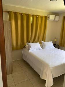 um quarto com uma cama branca e uma cortina amarela em Miki Miki Surf Lodge em Moorea