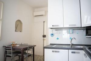 eine Küche mit weißen Schränken und einem Tisch mit einer Spüle in der Unterkunft Antonia Jess Central ,Near Beach- by Gessica homes in Monopoli