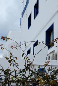 een wit gebouw met blauwe ramen en een boom bij Hostal Costa in Ibiza-stad
