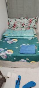 a bed with a green comforter with flowers on it at Matinxs Home in Abu Dhabi