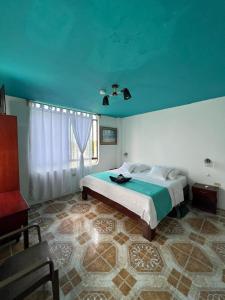 a bedroom with a bed with a blue ceiling at Hostal Brisas Del Mar in Puerto Villamil