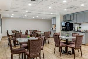 a restaurant with tables and chairs and a kitchen at Best Western Plus New England Inn & Suites in Berlin