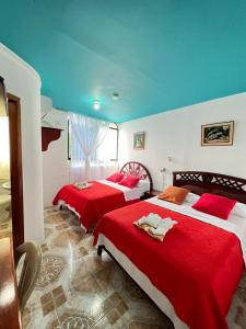 2 Betten in einem Hotelzimmer mit roter Bettwäsche in der Unterkunft Hostal Brisas Del Mar in Puerto Villamil