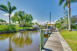 un canal con un muelle de madera y palmeras en Canalfront Home with Dock and Pool 5 Mi to Ft Myers!, en North Fort Myers