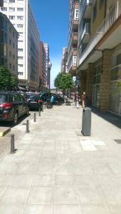 a sidewalk in a city with parked cars and buildings at APARTAMENTO GIJON - LA ARENA in Gijón