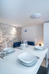a white table with plates and wine glasses on it at House Franulich in Stara Baška