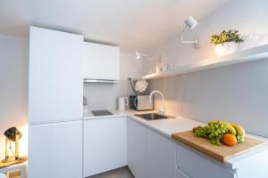 uma cozinha com armários brancos e fruta numa tábua de cortar em House Franulich em Stara Baška