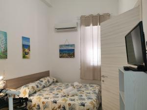 a bedroom with a bed and a flat screen tv at SOLE MIO Vacation in San Vito lo Capo