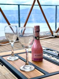 two wine glasses and a bottle on a table at Lujoso Glamping MarQua Spa Guatavita Wifi Cocina in Guatavita