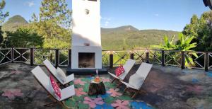 a patio with chairs and a fireplace with mountains in the background at Casa Ortmann in Canela