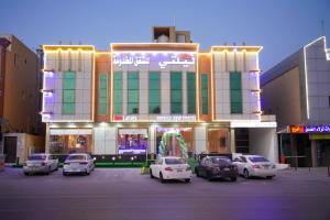 Un edificio con coches aparcados en un estacionamiento. en هذه ليلتي فرع النجاح باليرموك- This Lailaty Al Nagah Branch, en Riad