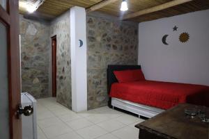 um quarto com uma cama vermelha e uma parede de pedra em Cha'skas Checkta Eco-Lodge em Santa Rosa de Quives