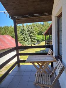 una mesa de picnic de madera y 2 sillas en el porche en Wypoczynek Mazurska Górka domki 2 osobowe, en Stare Juchy