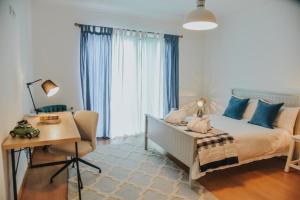 Un dormitorio con una cama con almohadas azules y un escritorio. en Quinta do Brasil, en Ribeira do Raposo 39 fotos más