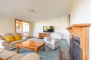 a living room with a couch and chairs and a tv at Sea views from holiday home in Lower Hutt