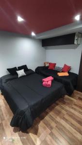 two beds in a room with black sheets and red pillows at EnSueños Bariloche in San Carlos de Bariloche
