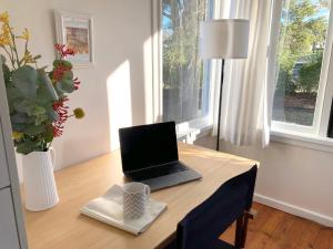 - un ordinateur portable assis sur un bureau en bois avec une fenêtre dans l'établissement Hamlet House, à Eden