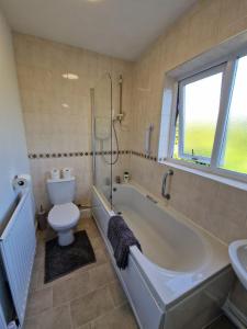 uma casa de banho com uma banheira, um WC e um lavatório. em Swanley Guest House em Kent