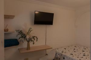 a bedroom with a bed and a television on the wall at Casa Blanca estadio in Medellín