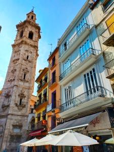 una torre de reloj alta junto a un edificio con sombrillas en Hotel El Siglo, en Valencia