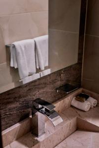 y baño con lavabo, espejo y toallas. en Hotel Casa Cantera, en Oaxaca City