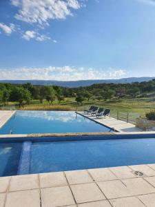 een zwembad met 2 stoelen en uitzicht op een veld bij LA TOSCANA casas y suites in Nono