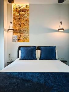 a bedroom with a large bed with blue pillows at Hotel El Siglo in Valencia