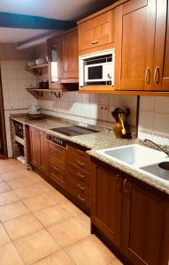 kuchnia z drewnianymi szafkami i białą kuchenką mikrofalową w obiekcie Las maletas del pasiego w mieście Quintana